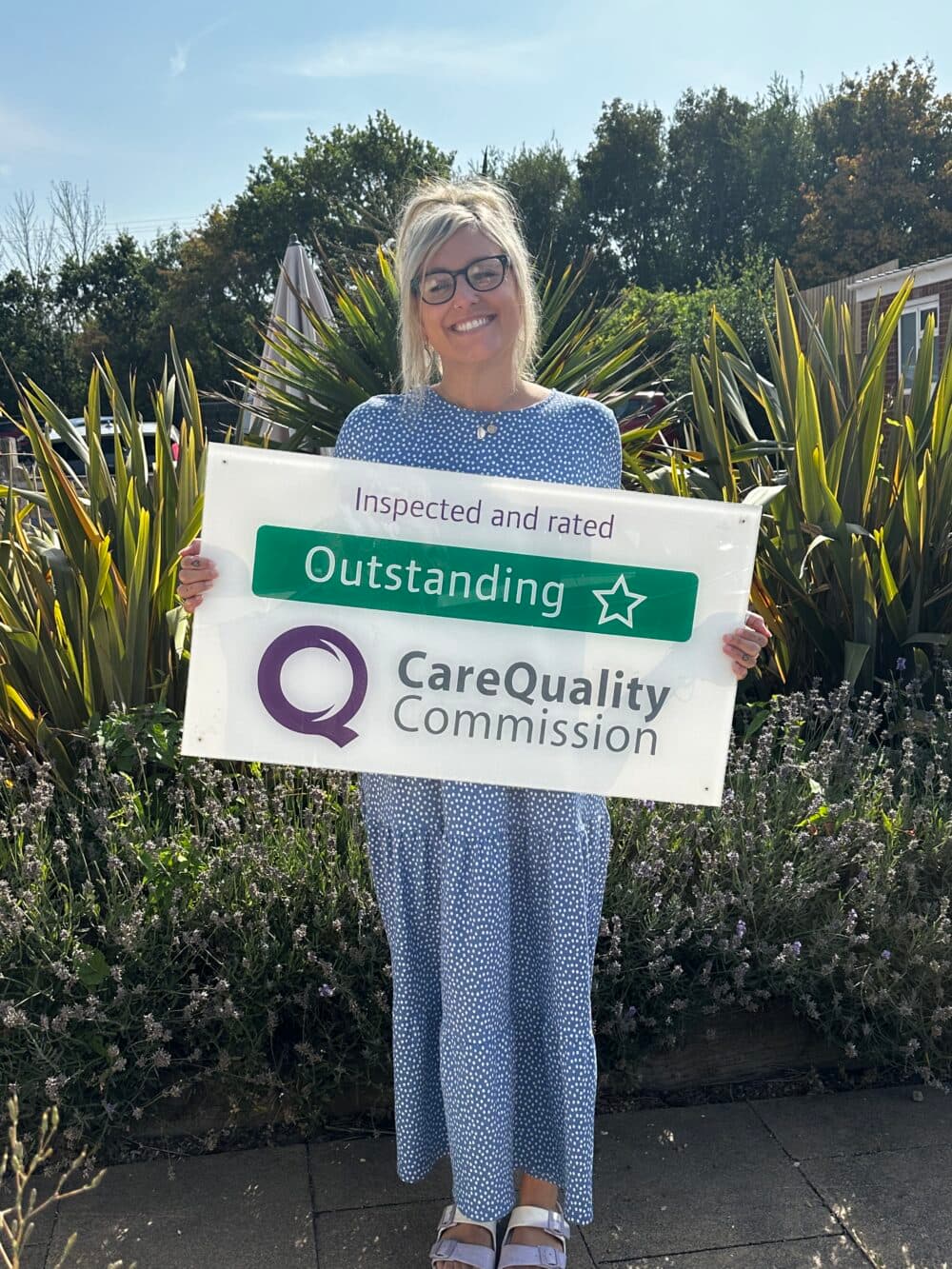 Blonde lady holding an outstanding CQC Sign
