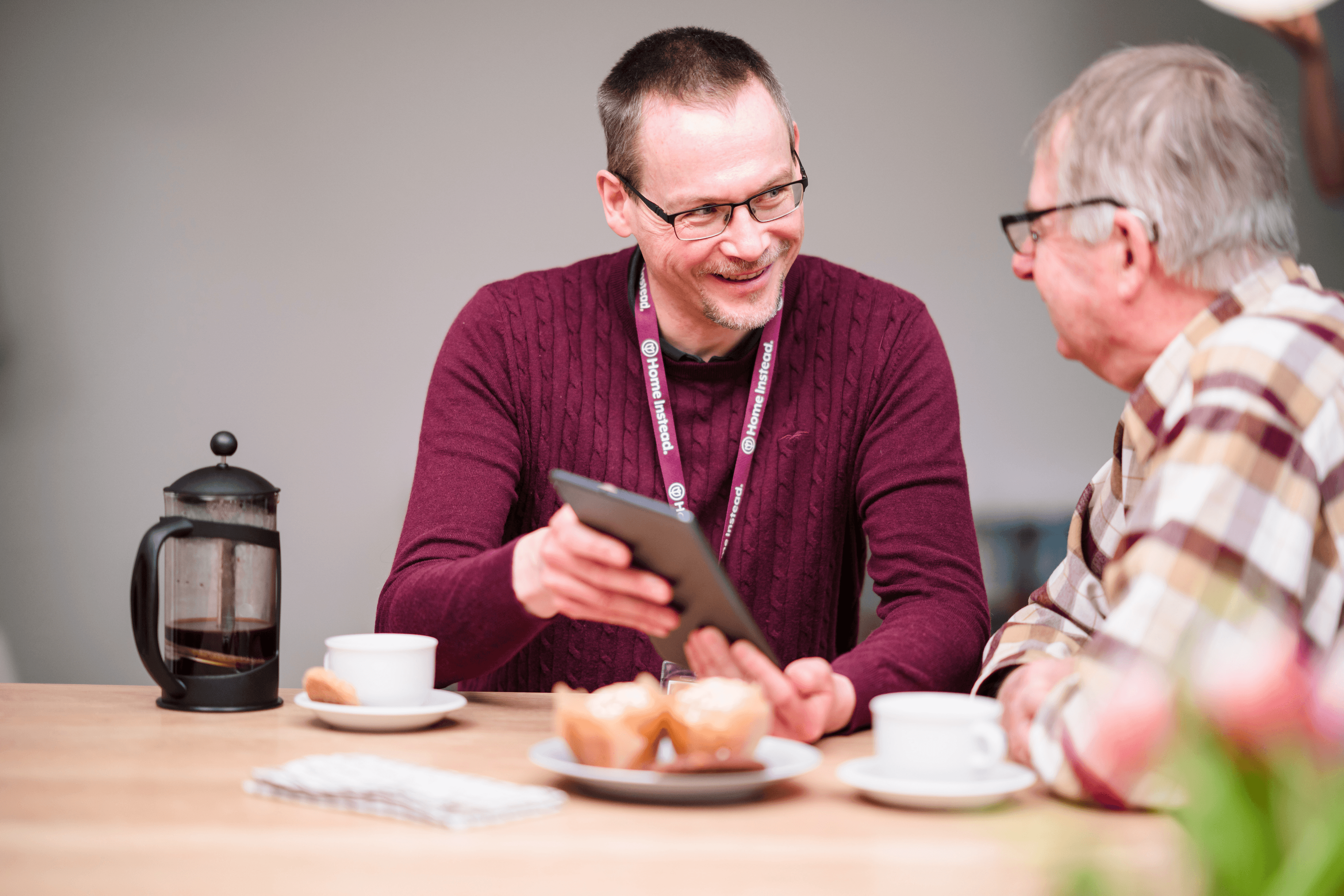 A Care Professional smiling whilst using a tablet with a client