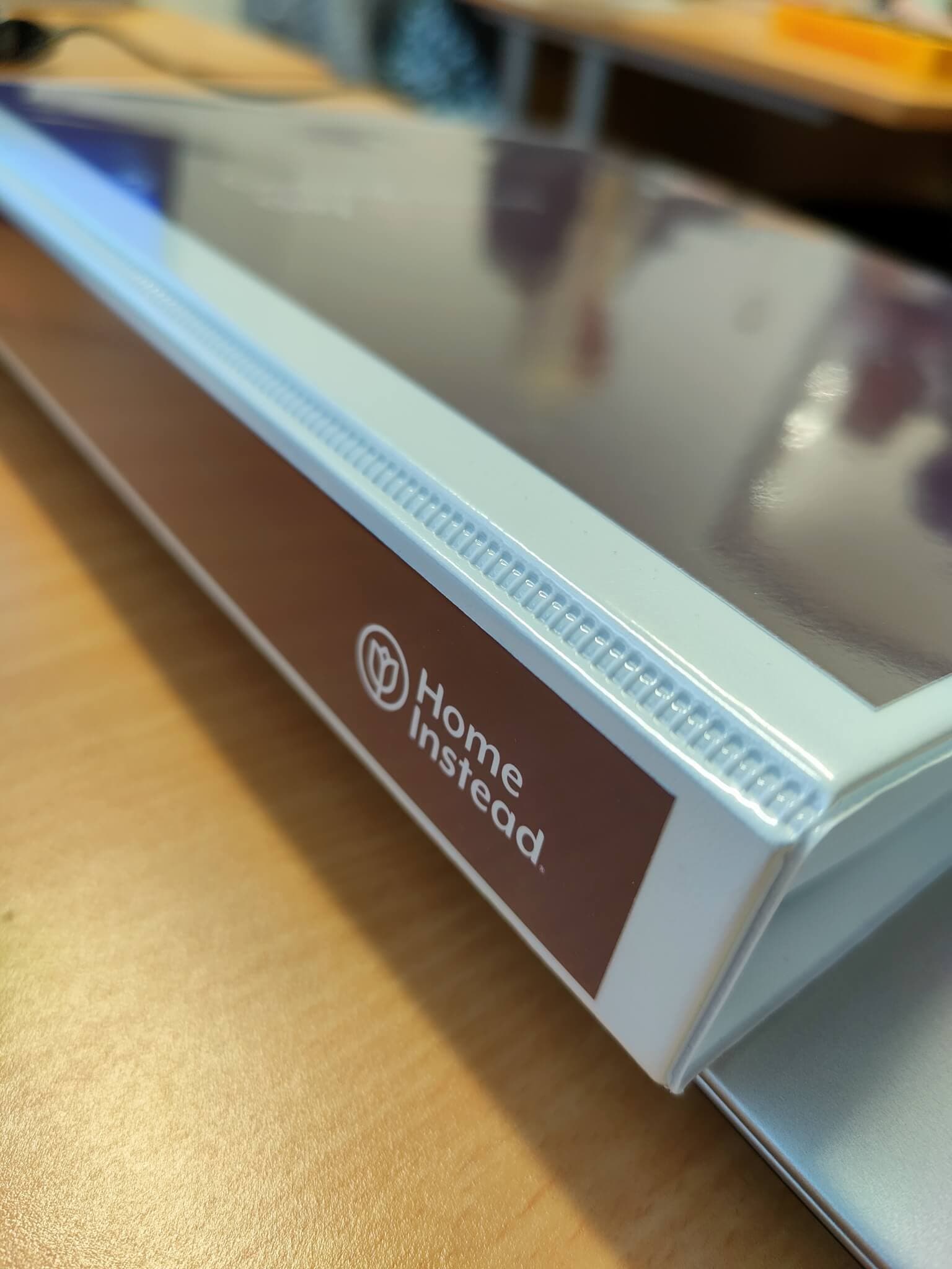 A close-up image of a sign that reads "Home Instead" on a desk folder. - Home Instead