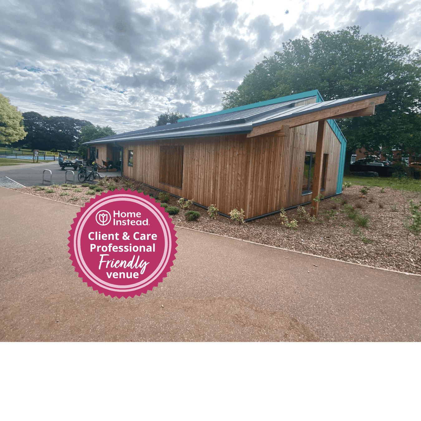 A modern wooden building with a badge stating, "Home Instead Client & Care Professional Friendly Venue" in the foreground. - Home Instead