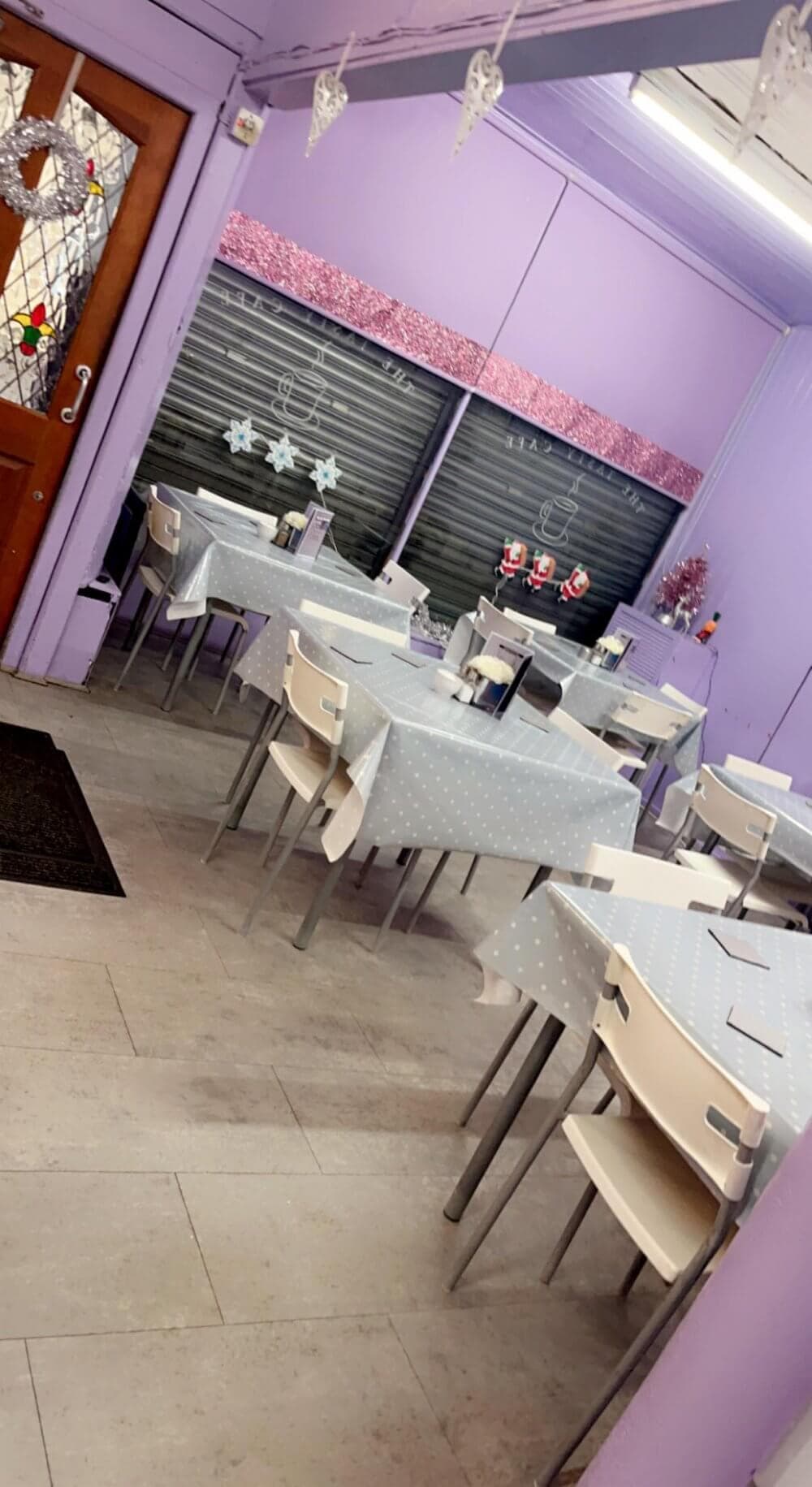 The Tasty Cafe, Johnstone - A small, empty cafe with lilac walls, white chairs, and polka-dot tablecloths. Decor includes star-shaped wall ornaments. - Home Instead Renfrewshire and Barrhead home care services