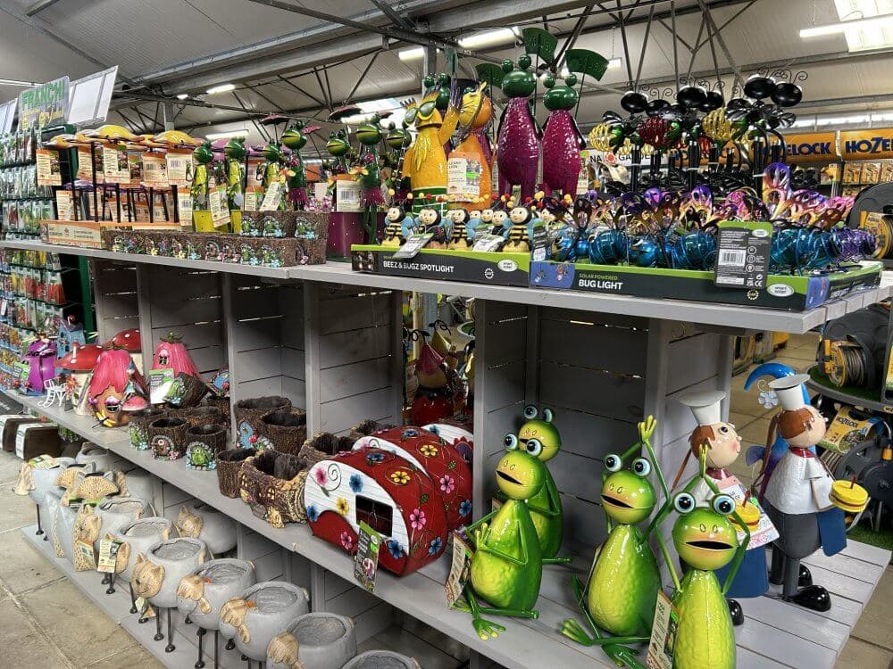 Home Instead Basingstoke picture of Elm Park Garden Centre, Tadley, showing shelving unit with colourful garden ornaments, including frogs, gnomes and bugs