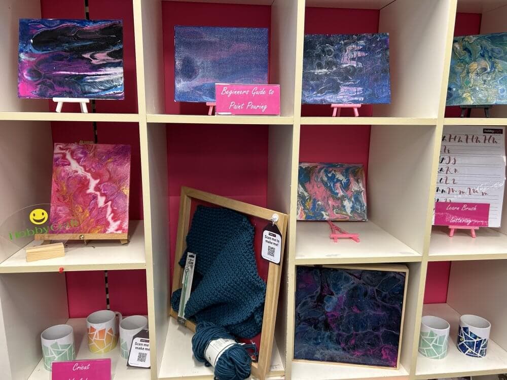 Home Instead Basingstoke picture of colourful artwork, knit fabric and craft supplies arranged on white shelves at Hobbycraft in Basingstoke