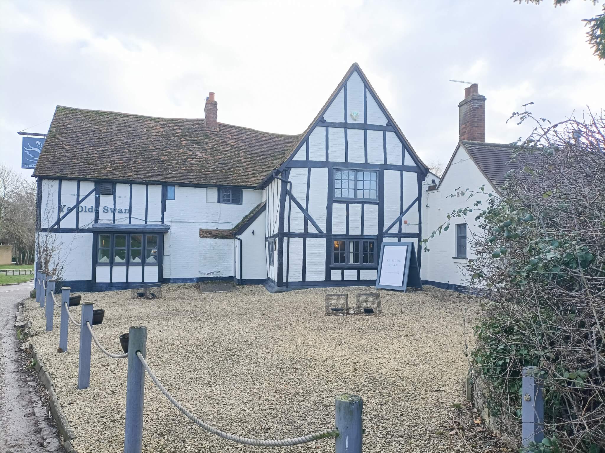 A traditional white and black timber-framed building with a gabled roof and a sign that reads "Old Swan. - Home Instead