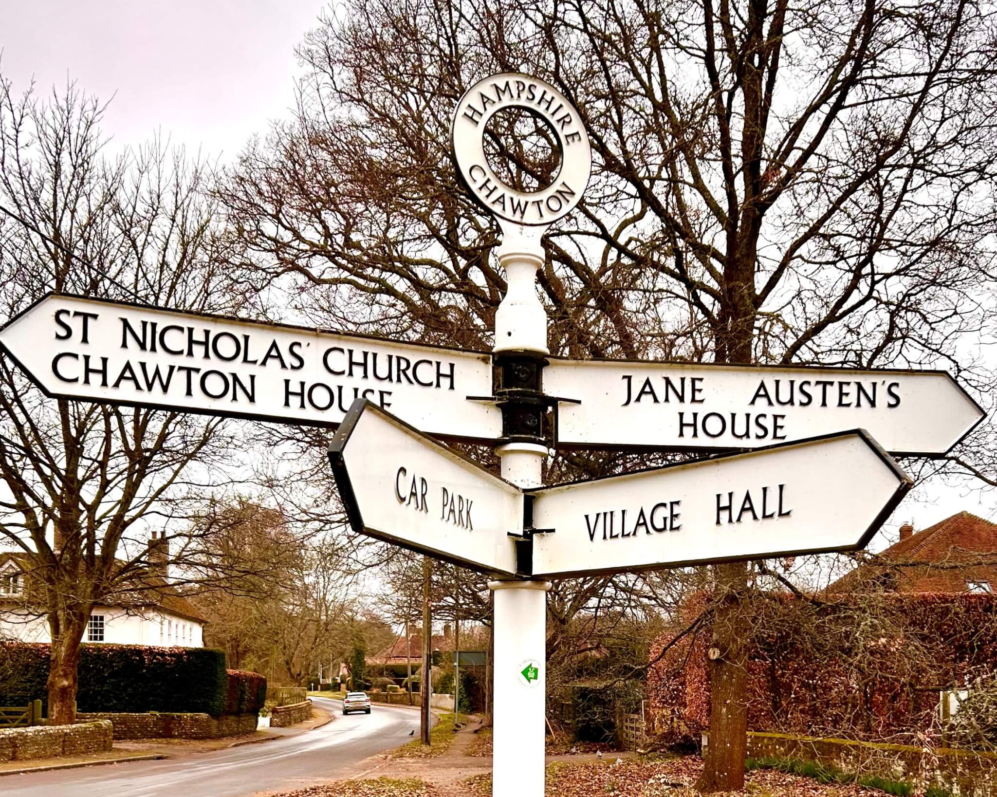 Home Instead Basingstoke picture of a signpost in Chawton, Hampshire, pointing to St Nicholas' Church, Chawton House, Jane Austen's House, the car park, and Village Hall