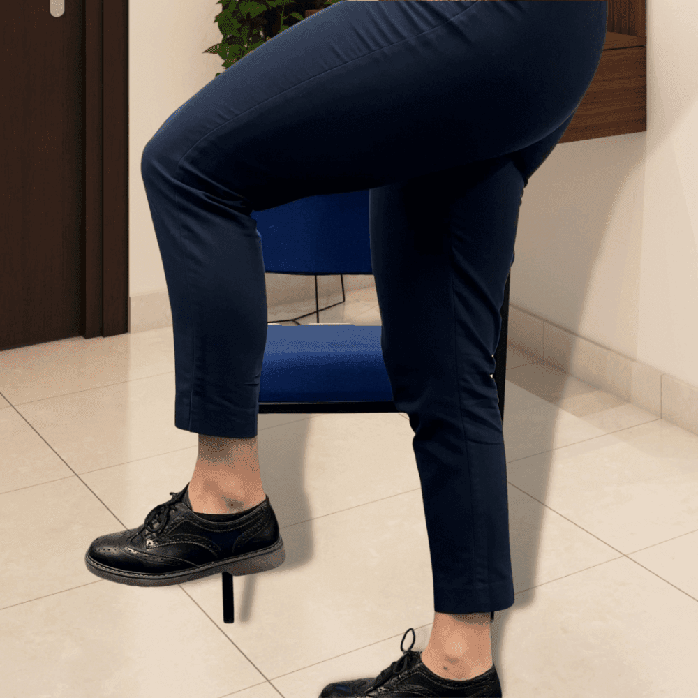 A person in blue pants and black shoes is lifting their right leg while seated on a blue chair. - Home Instead