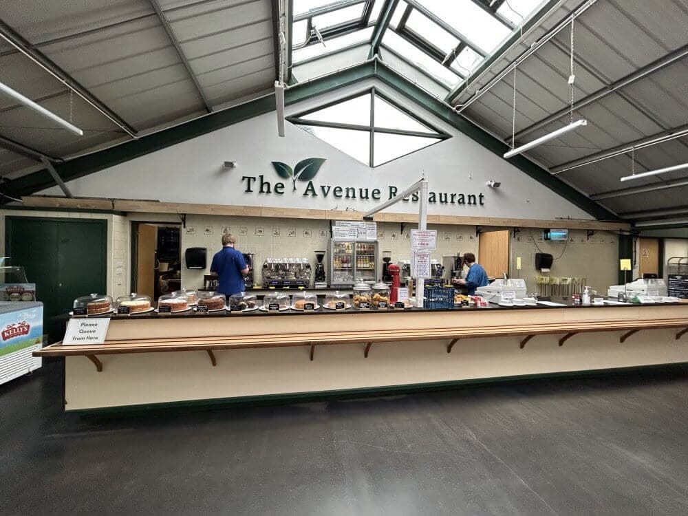 Home Instead Basingstoke picture of The Avenue Restaurant at The Avenue Nurseries Garden Centre, showing food counters with baked goods, coffee machines and people working behind the counter.