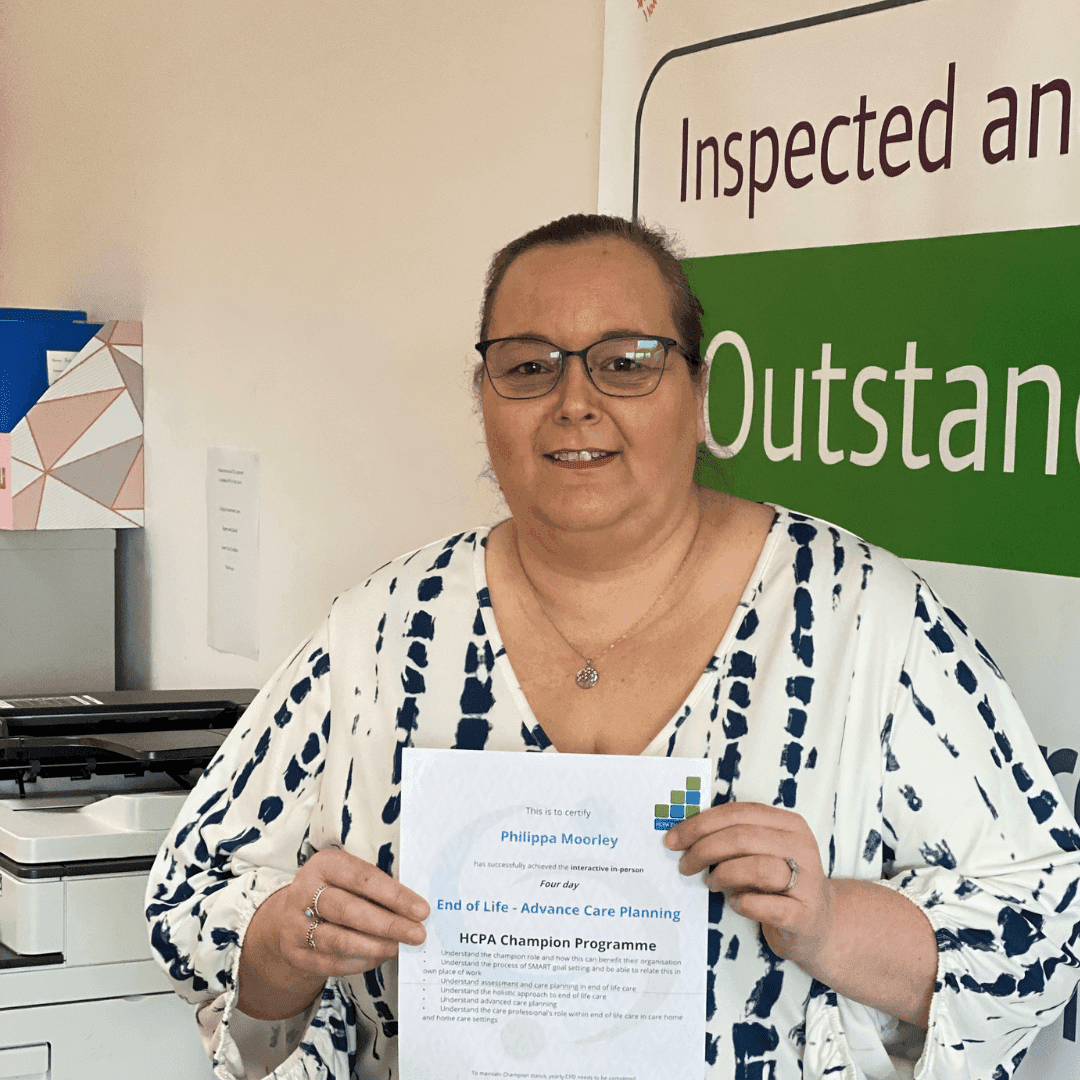 A woman holding a certificate stands in front of a sign reading "Inspected and Outstanding. - Home Instead