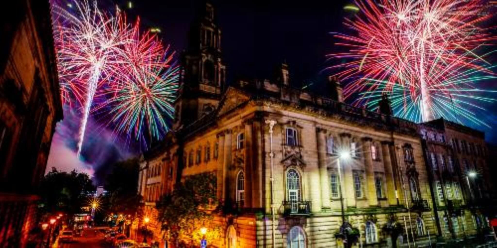 A historic building illuminated by colorful fireworks in the night sky. Celebratory atmosphere with bright lights. - Home Instead
