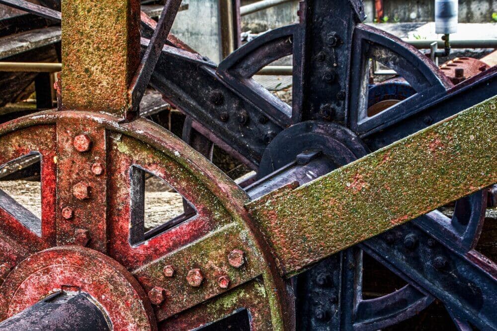Close-up of rusty, weathered metal gears and machinery in an industrial setting. - Home Instead