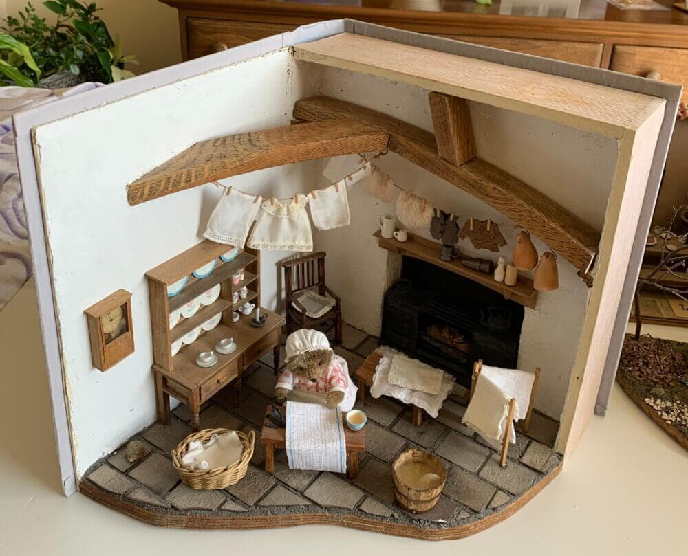 A detailed miniature rustic room with furniture, a stove, drying laundry, and a cozy atmosphere. - Home Instead