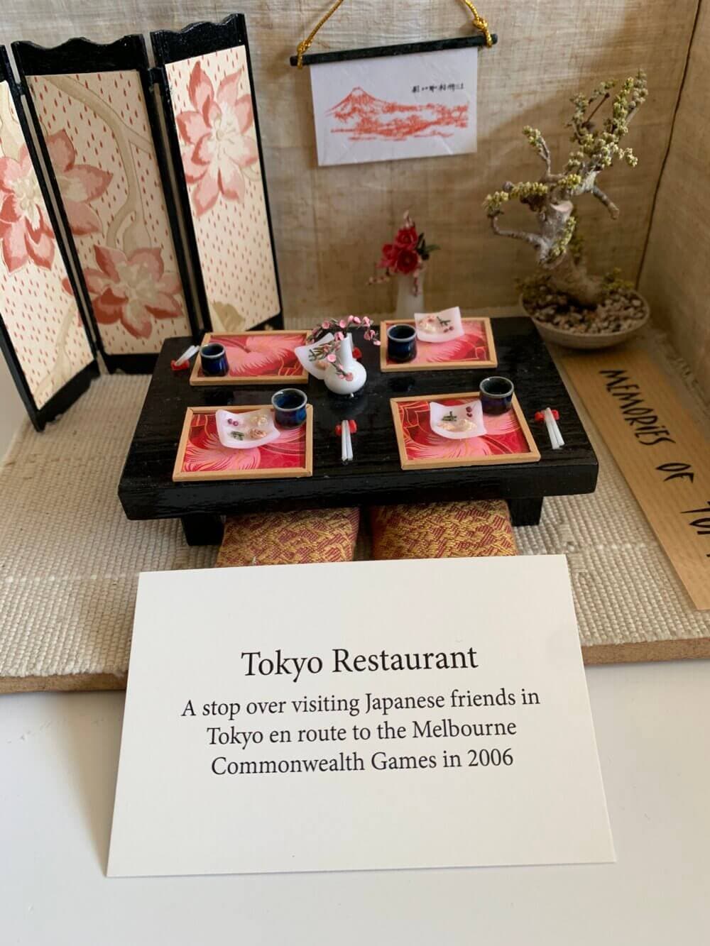 A miniature display of a Japanese-style dining table with small dishes and decor, labeled "Tokyo Restaurant. - Home Instead