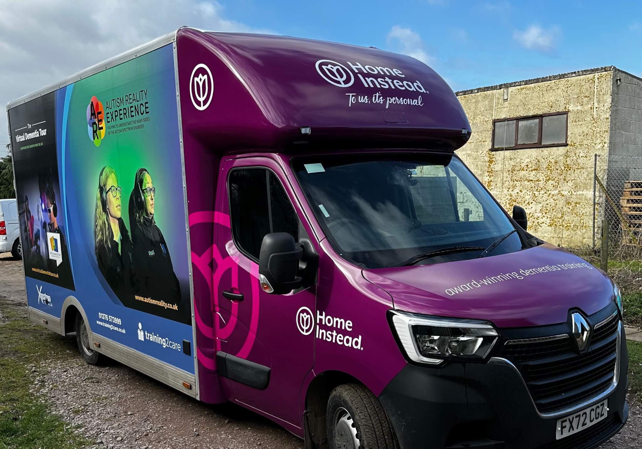 A purple and blue truck with "Home Instead" branding and "Autism Reality Experience" graphics. License plate FX72 CCJ. - Home Instead
