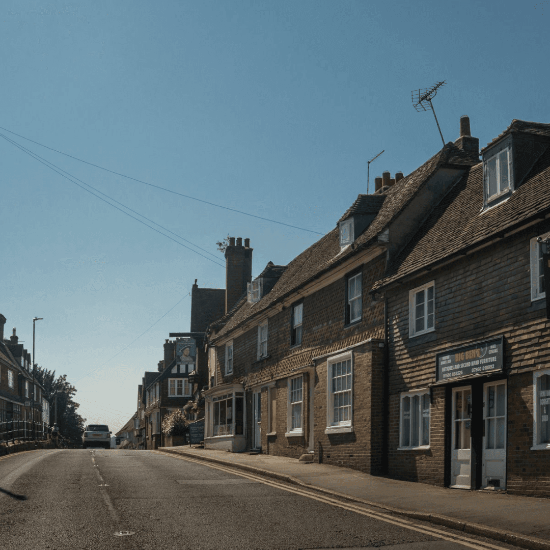 A quiet street in a small town with brick buildings, a shop, and a clear blue sky overhead. - Home Instead