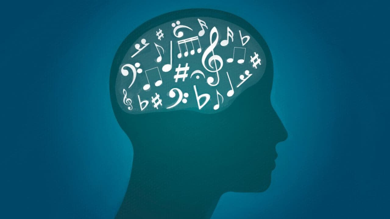 Silhouette of a head with a brain filled with various musical notes and symbols on a blue background. - Home Instead