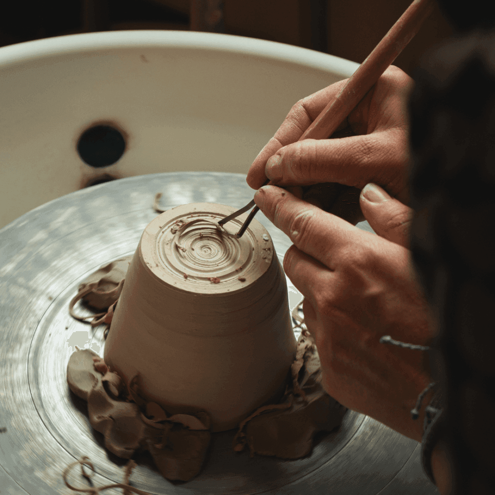 Hands carving patterns into a clay pot on a spinning pottery wheel. - Home Instead