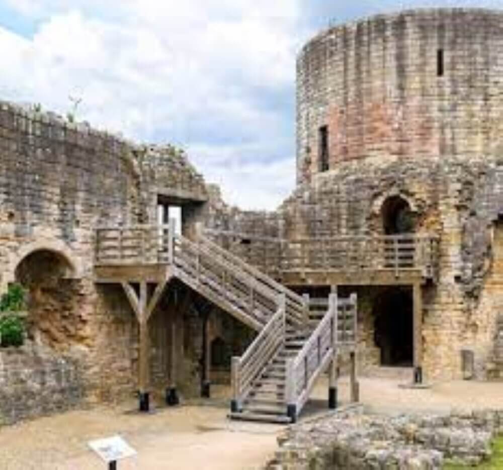 Ancient stone castle ruins with wooden stairways and a round tower under a cloudy sky. - Home Instead