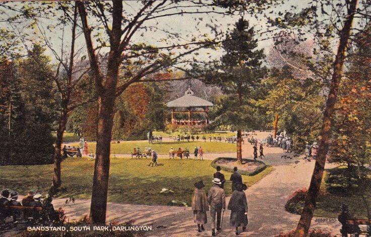 A park scene with people gathered around a bandstand in South Park, Darlington, surrounded by trees and walkways. - Home Instead