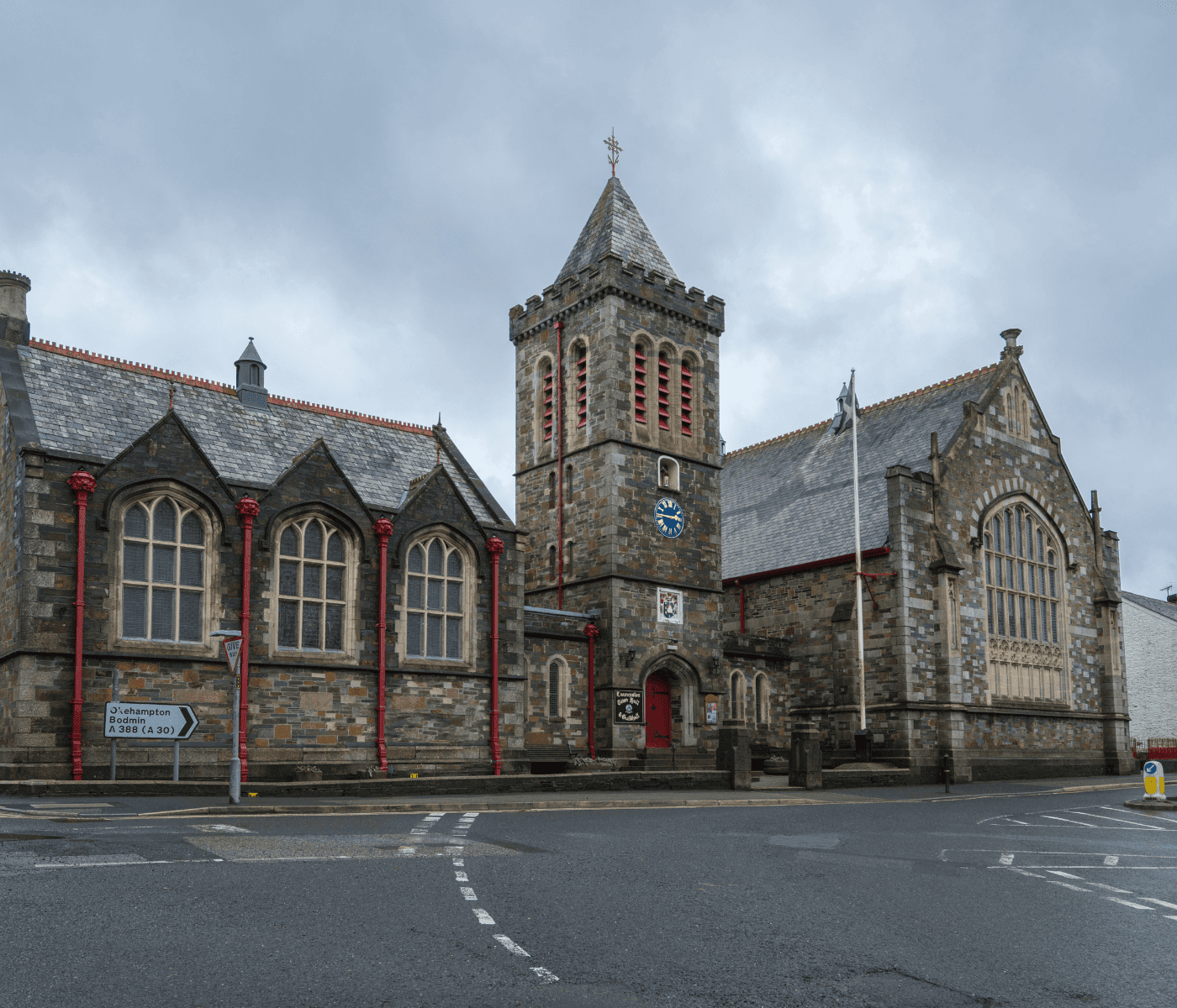 A stone church with a clock tower and arched windows on a cloudy day. - Home Instead