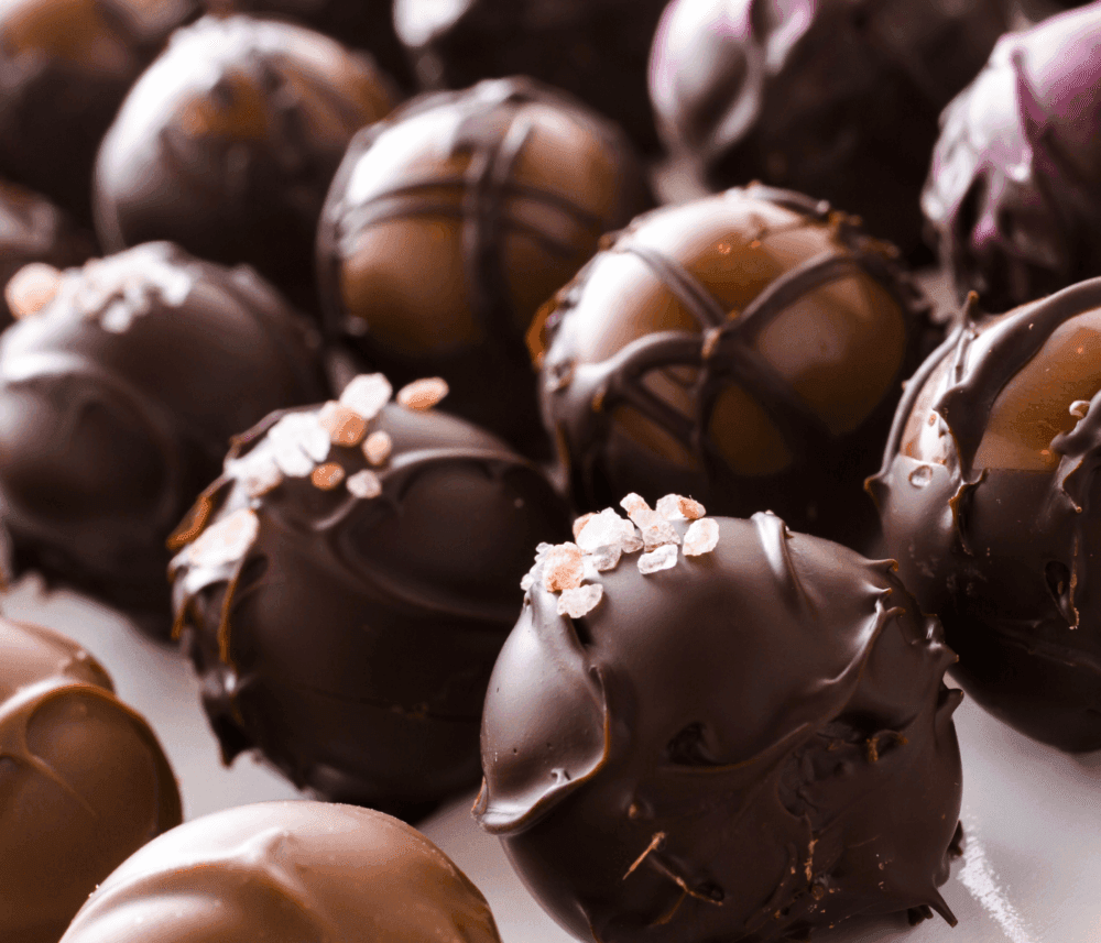 Close-up of various chocolate truffles with different toppings and drizzles, arranged in a pleasing pattern. - Home Instead