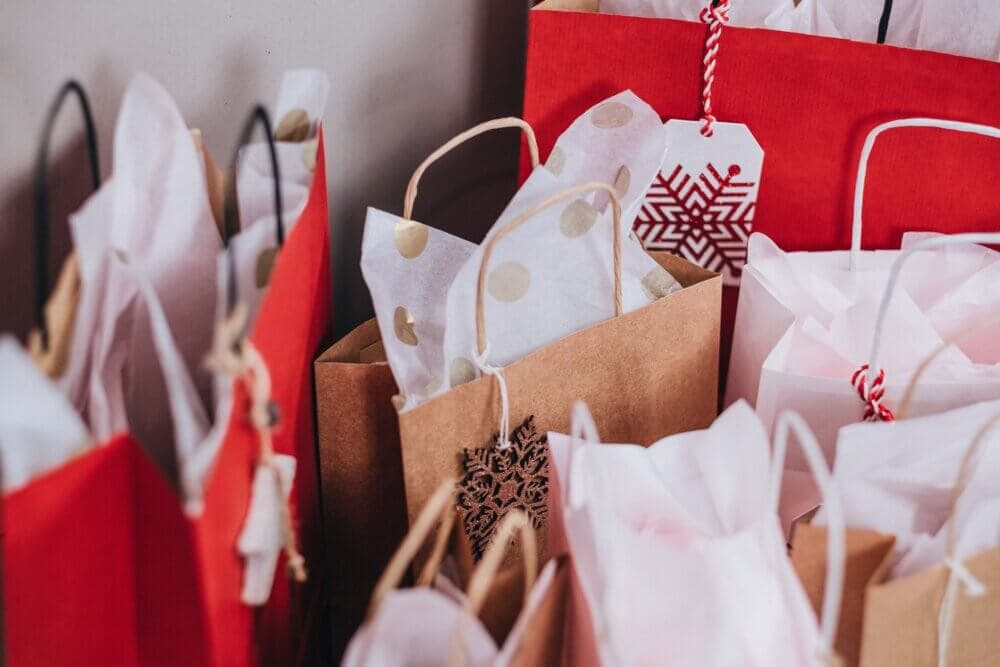 Gift bags in red, brown, and white with decorative tags and tissue paper, possibly for a festive occasion. - Home Instead