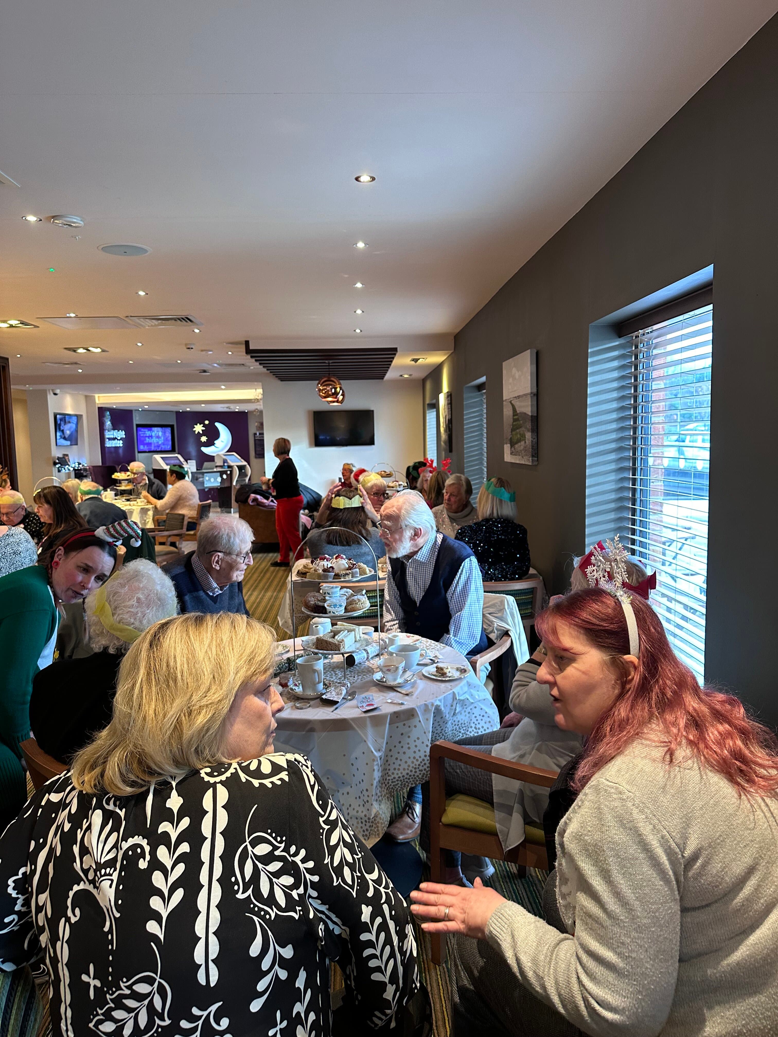 A group of people are socializing and enjoying a meal together in a restaurant setting. - Home Instead