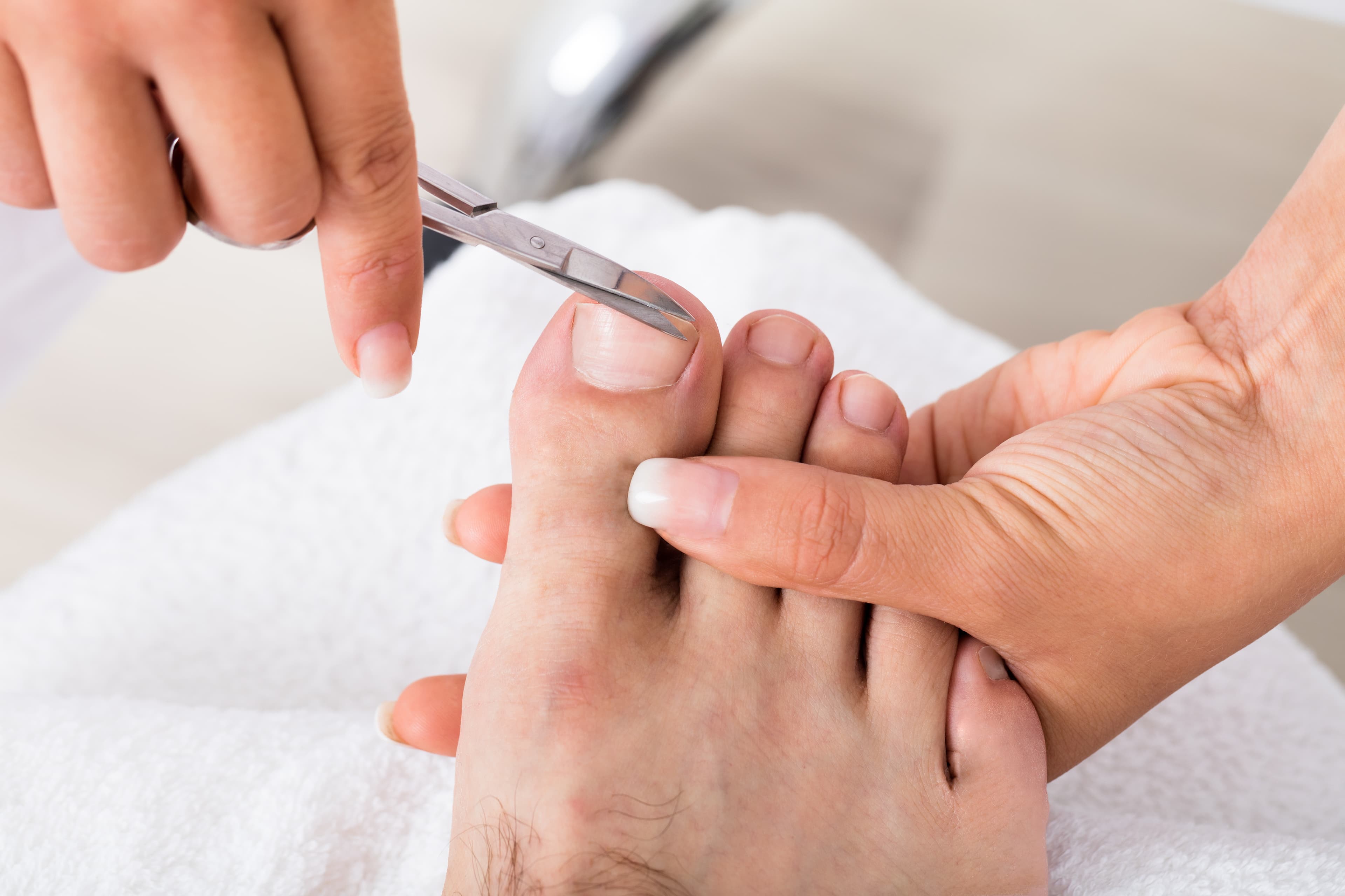 Close-up of a person trimming toenails with nail clippers while holding the foot steady. - Home Instead