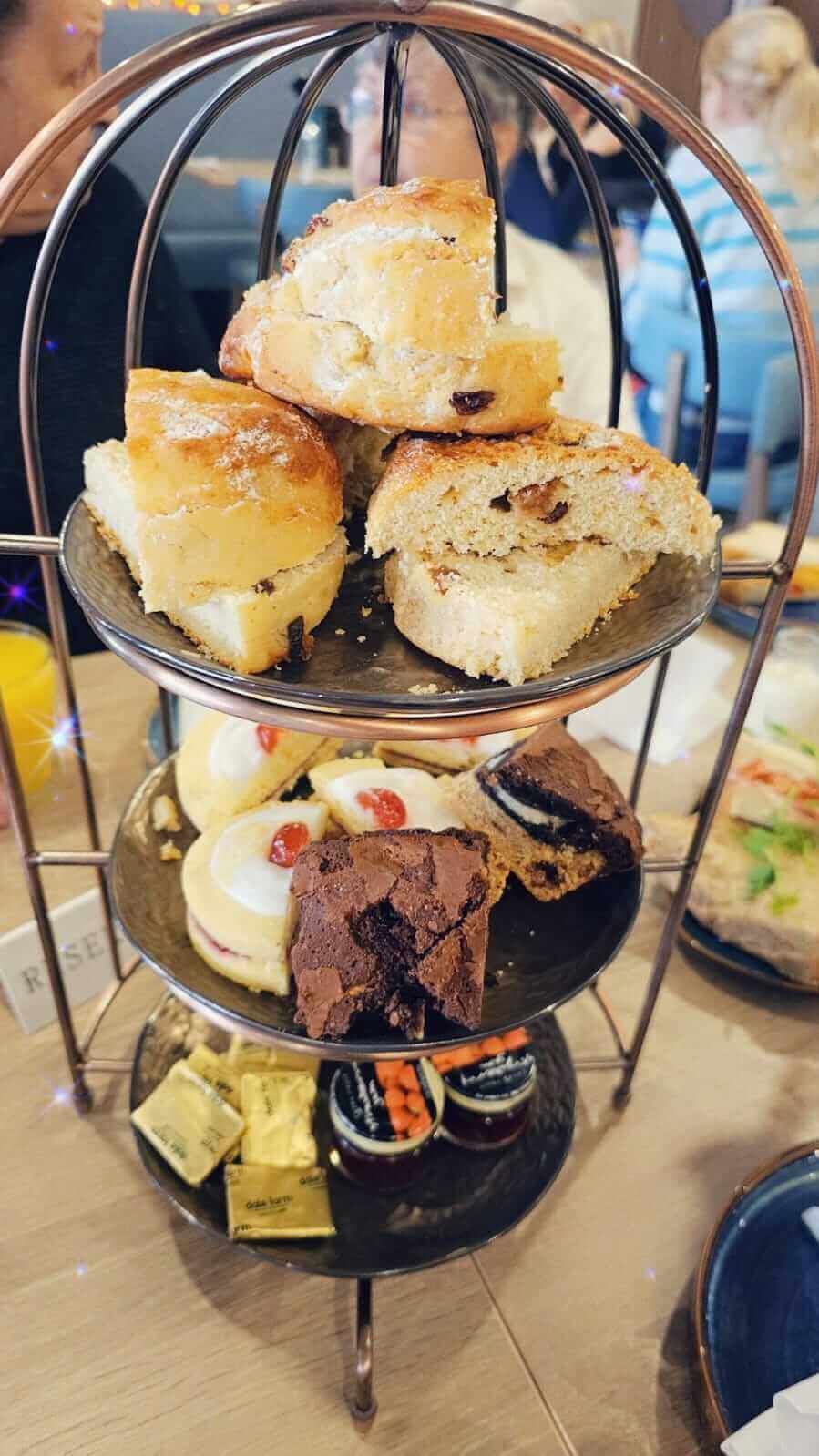 Three-tiered tray with scones, desserts, sandwiches, and condiments, set for an afternoon tea at Familia Cafe in Renfrew. - Home Instead Renfrewshire and Barrhead home care services - Free monthly client Get Together