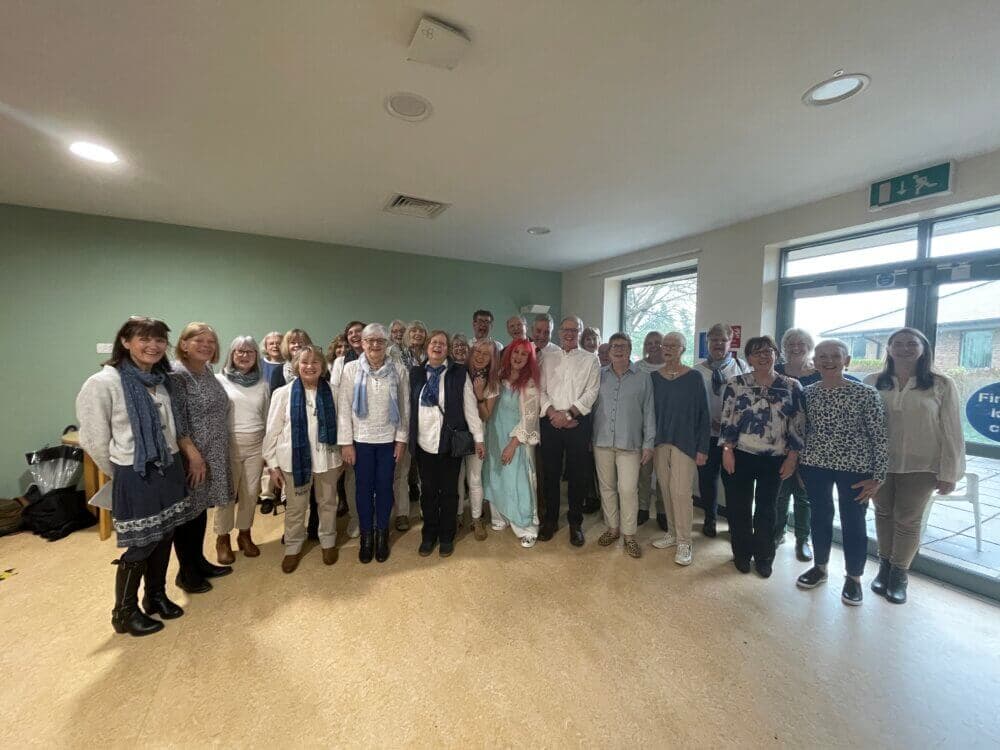 A group of people stands together in a room, smiling at the camera for a group photo. - Home Instead