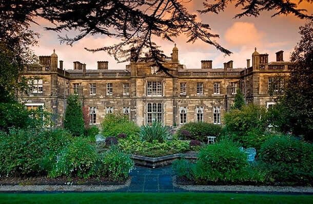Mar Hall - an Ornate historic building with a symmetrical facade, surrounded by lush gardens at sunset. - Home Instead Renfrewshire and Barrhead