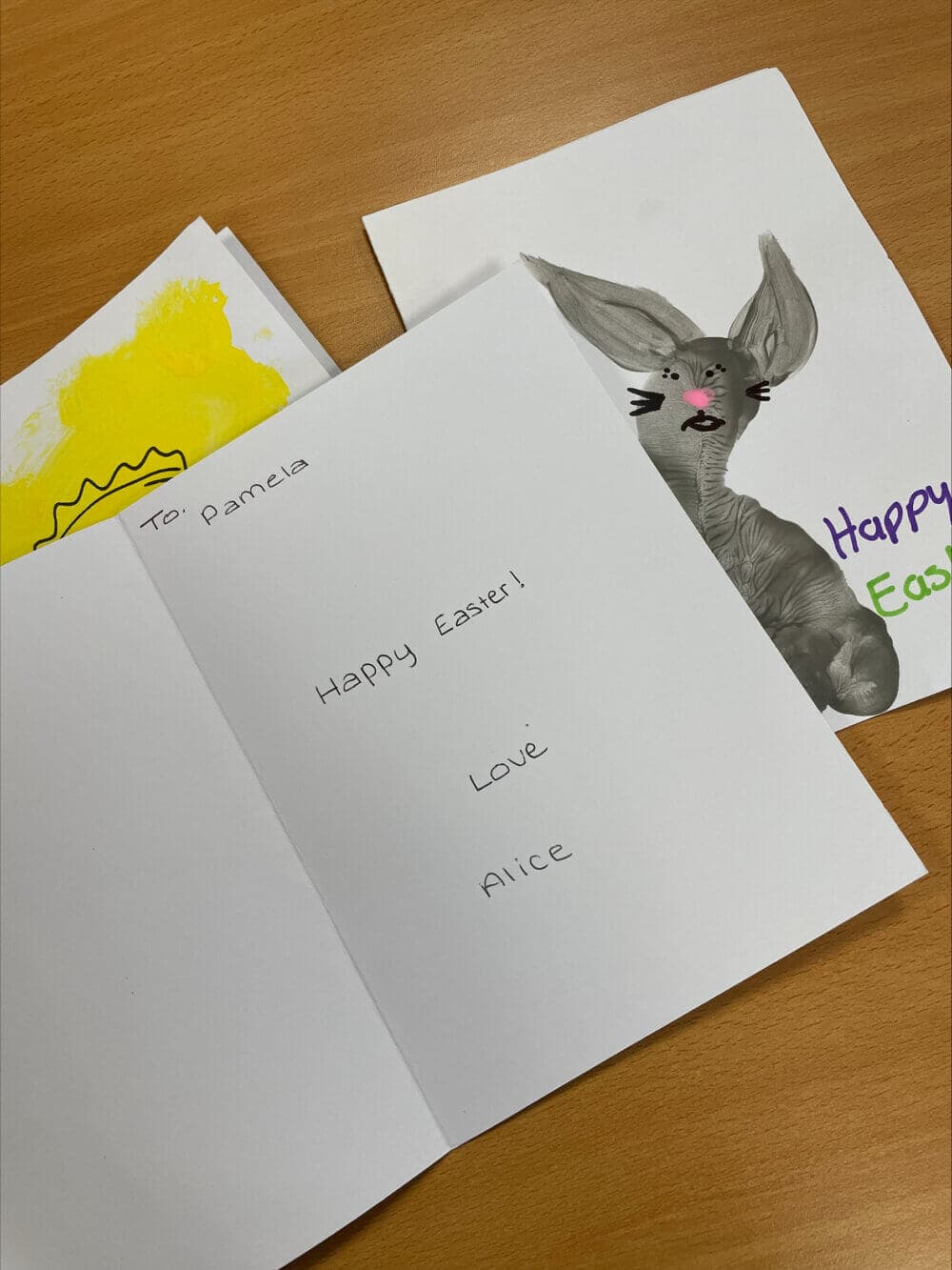 Two handmade Easter cards on a table, one open with a message and the other featuring a bunny drawing. - Home Instead
