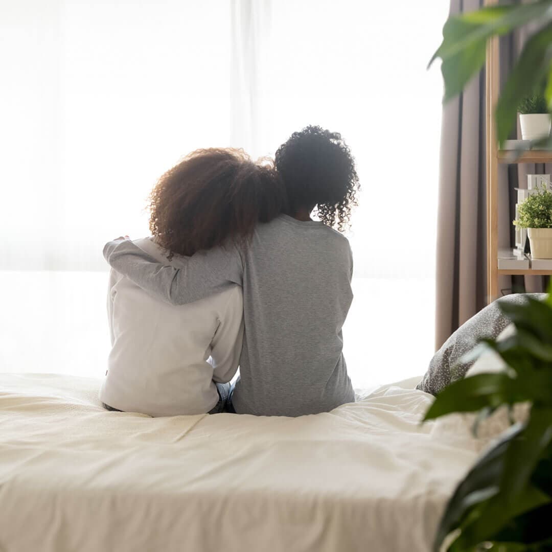 lady sat next to another with her arm around her shoulders offering support