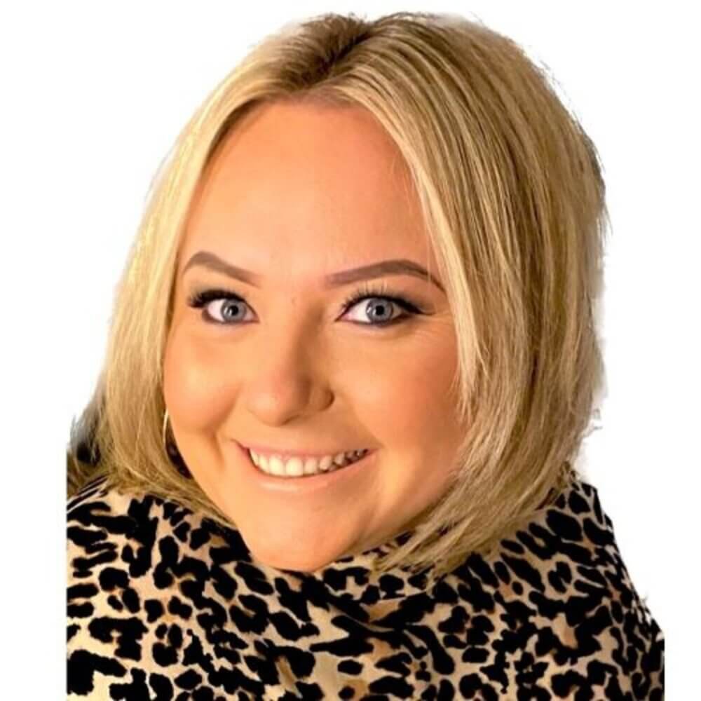 Blonde woman smiling, wearing a leopard print scarf, with a white background. - Home Instead