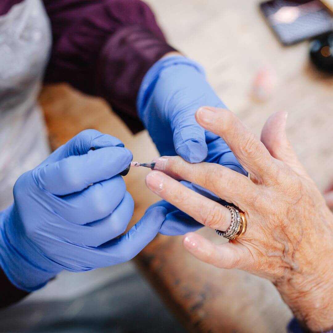 A lady is having her nails painted by a Home Instead Care Professional