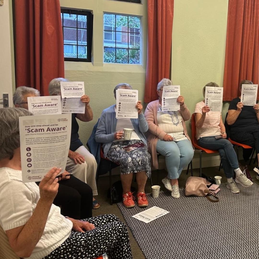 A room of ladies holding scam documents obscuring their faces