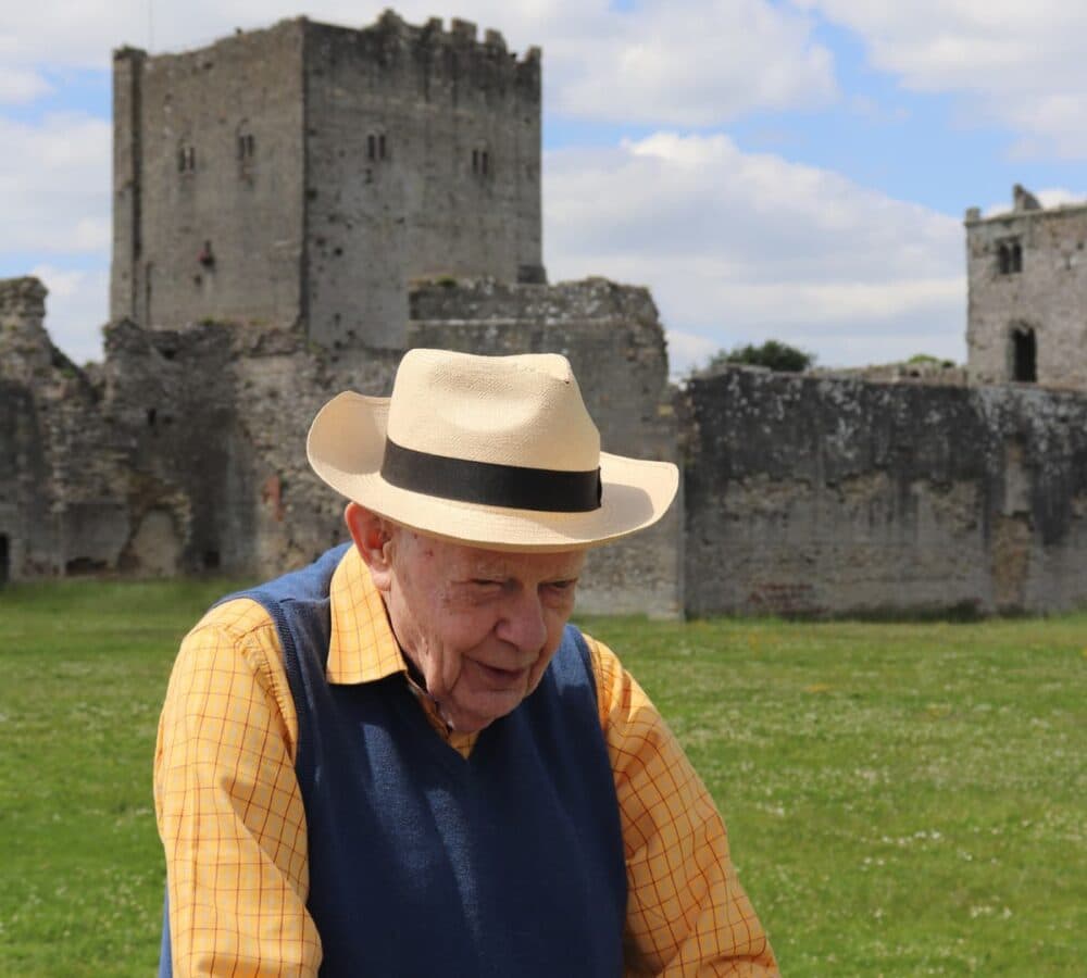 A senior man walking outdoors with a beautiful view and wearing a hat and yellow long sleeves