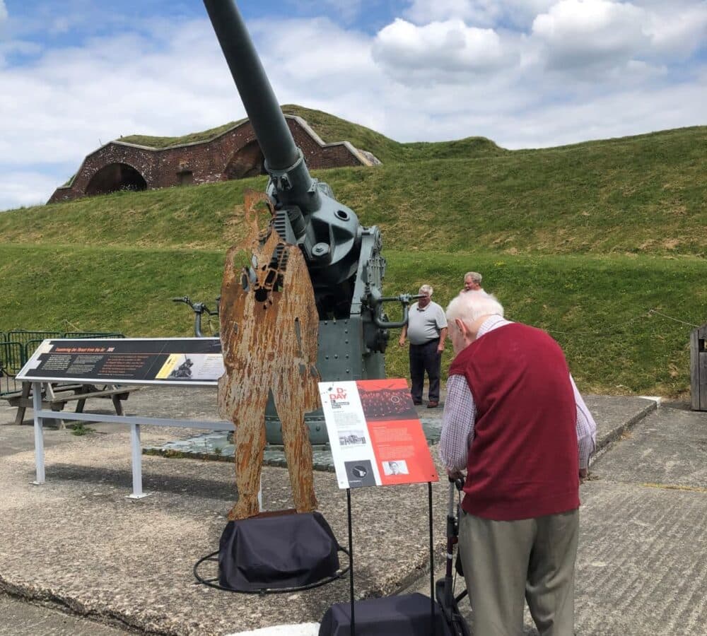 A senior man outdoors with a walker looking at an exhibit and reading the information