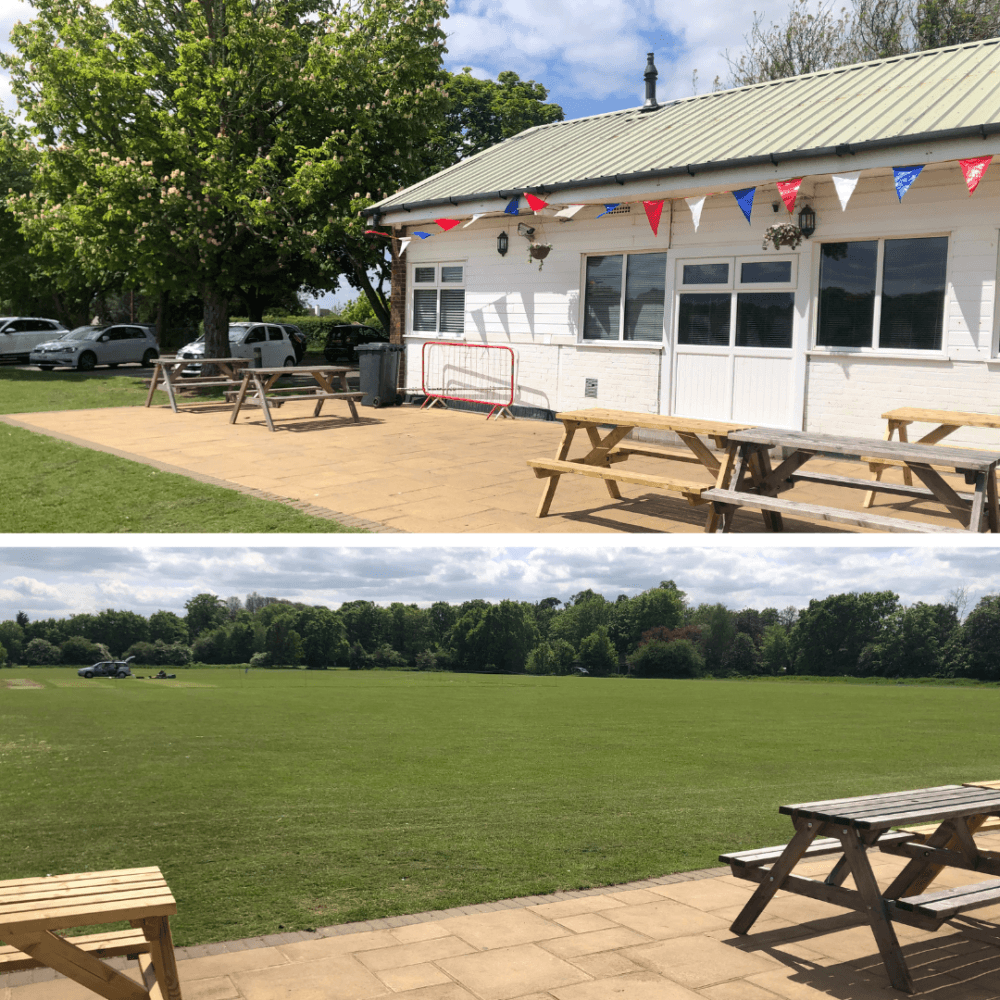 A clubhouse with colorful bunting and picnic tables next to a large grassy field under a partly cloudy sky. - Home Instead