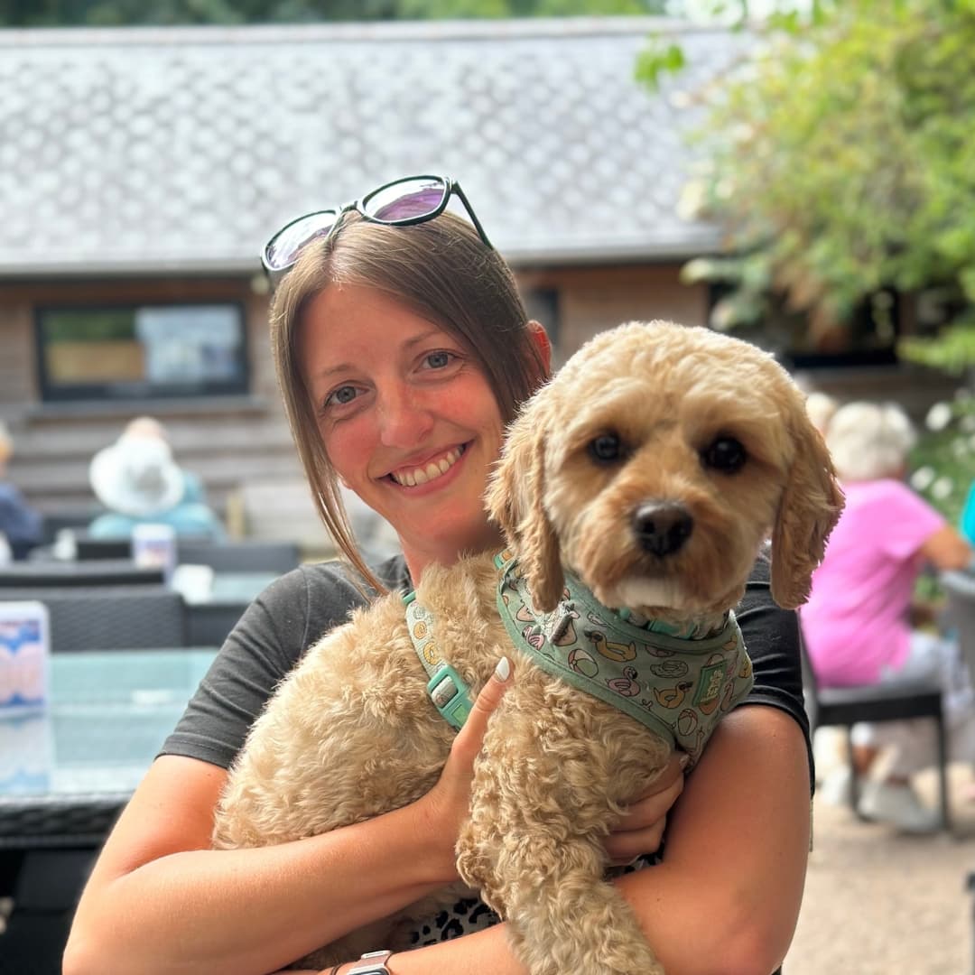 A lady sitting at a table holding a fluffy dog