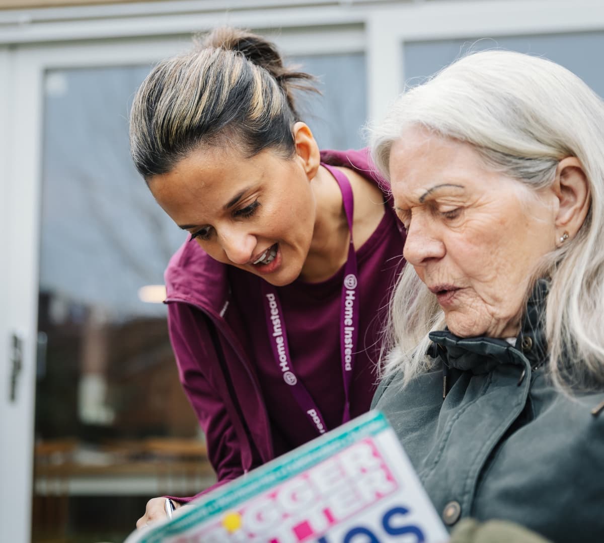 Senior with a younger carer outside the house and solving some puzzles