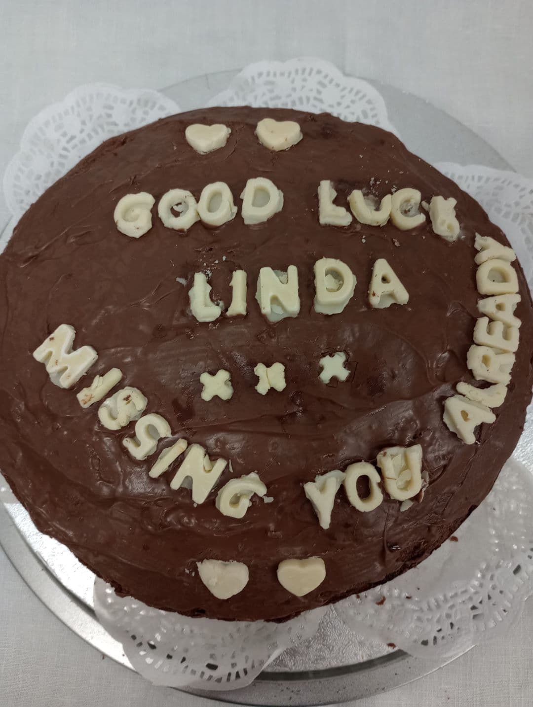 Chocolate cake with "Good Luck Linda, Missing You Already" written in white icing. - Home Instead