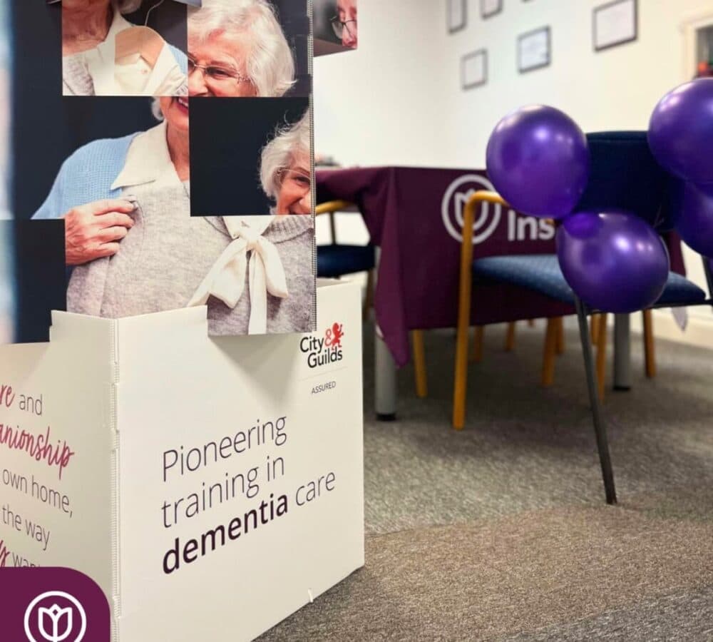 purple balloons tied on chairs inside a room with tables and some big photos