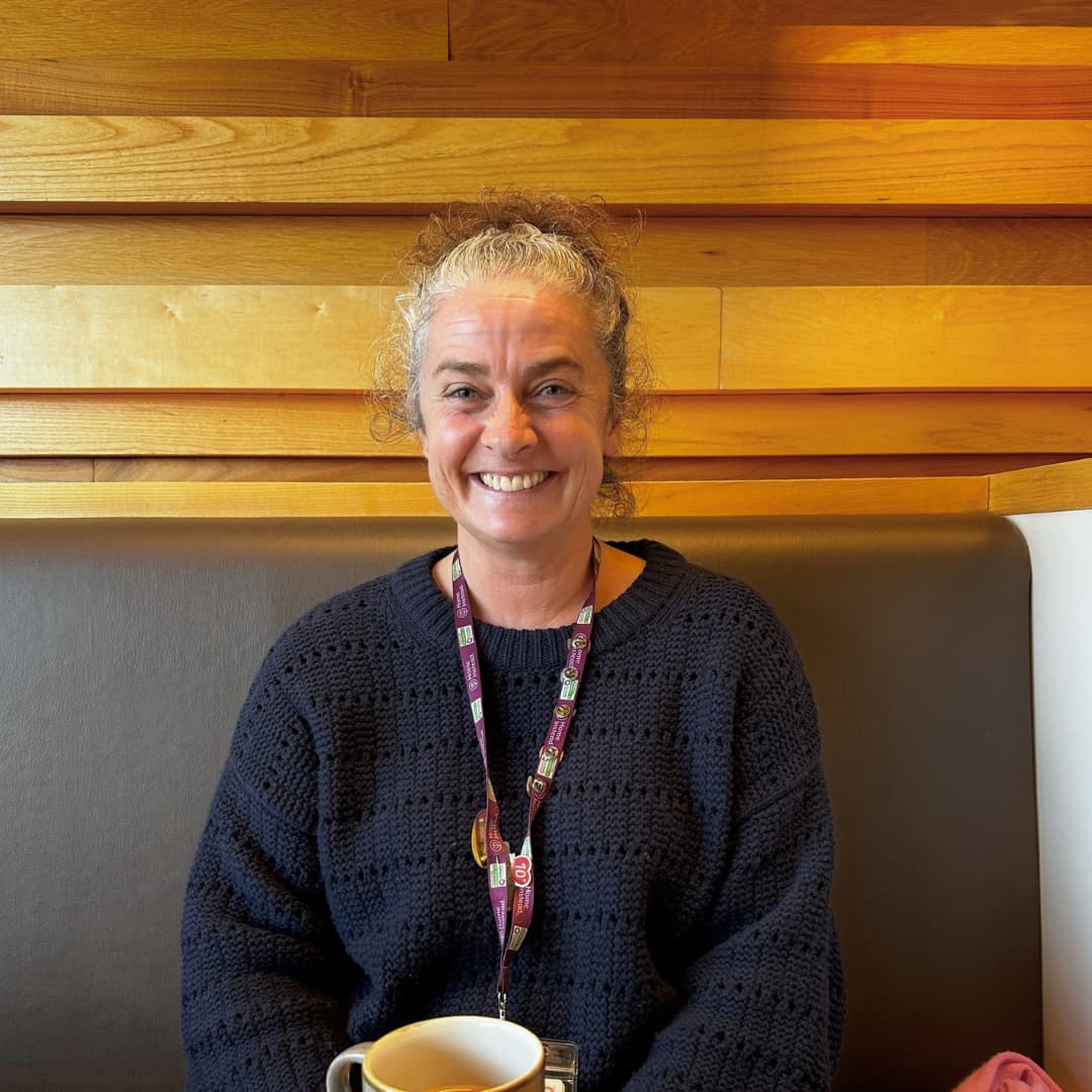 A lady smiling in a cafe with a cup of tea