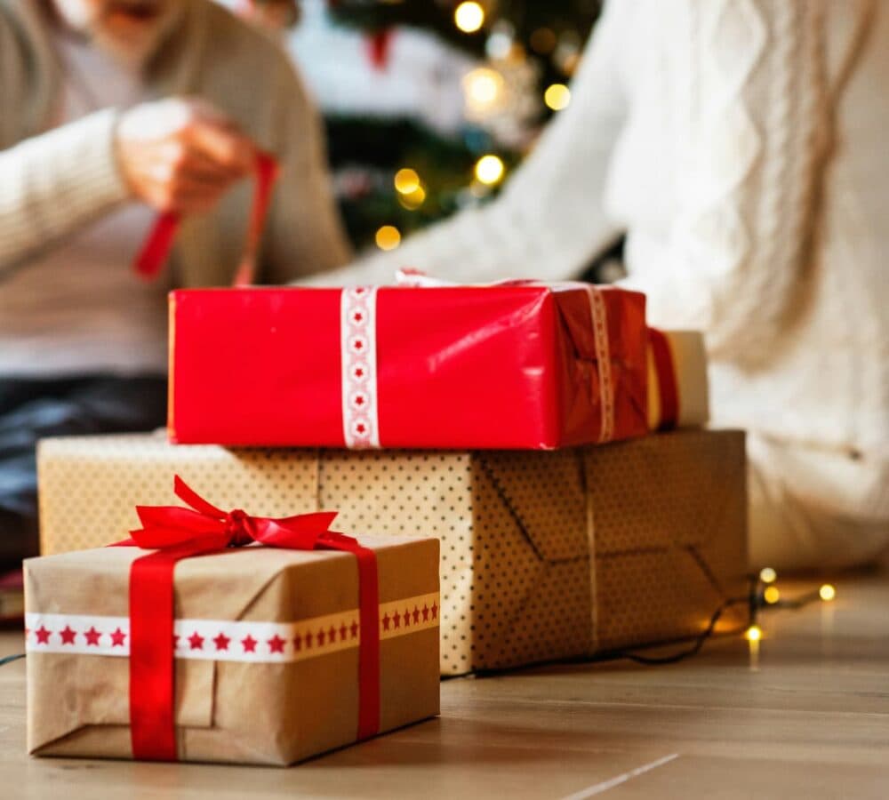 Gift boxes on the floor wrapped in red and brown with red ribbon