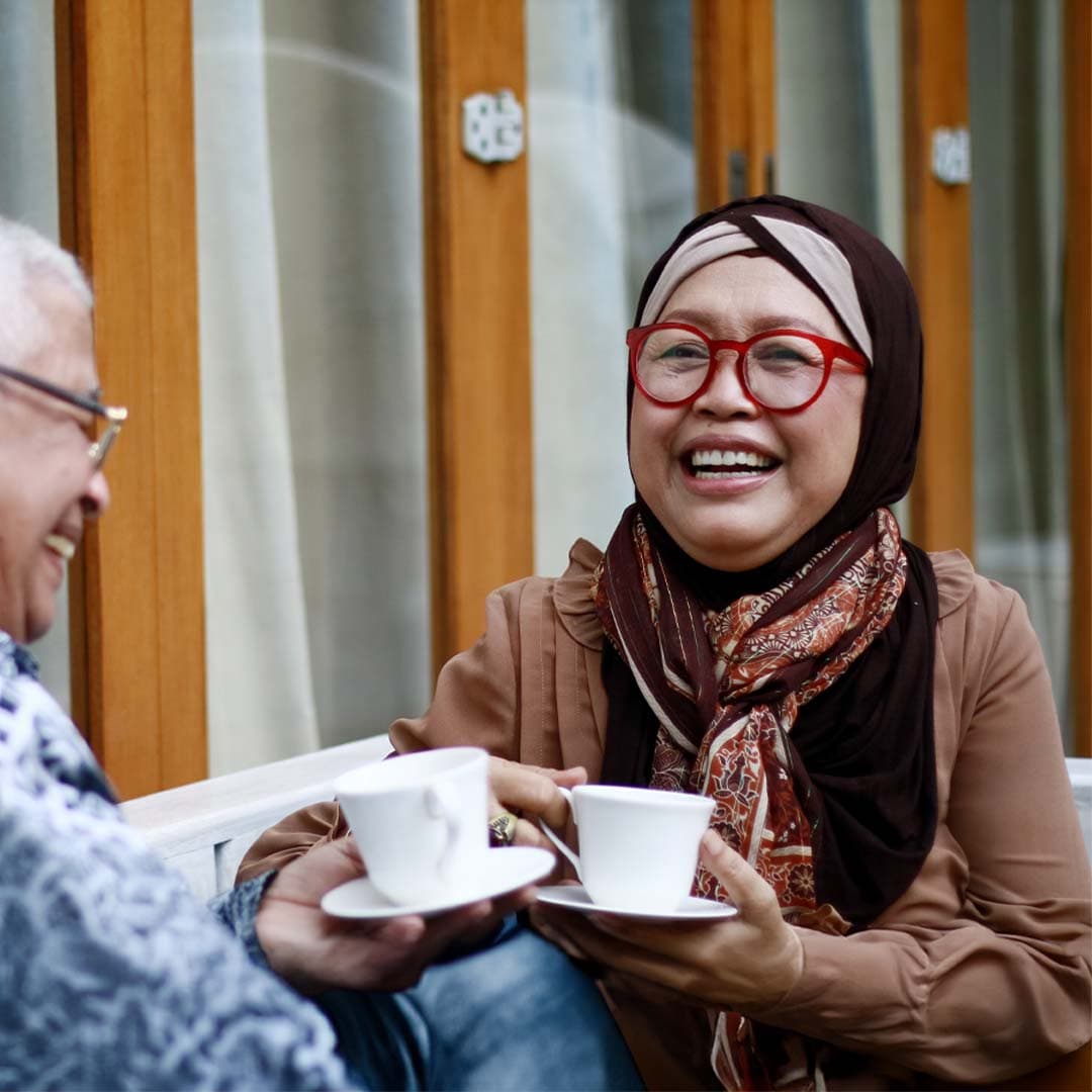 Muslim senior lady enjoying a cup of tea with her visiting Home Instead Care Professional