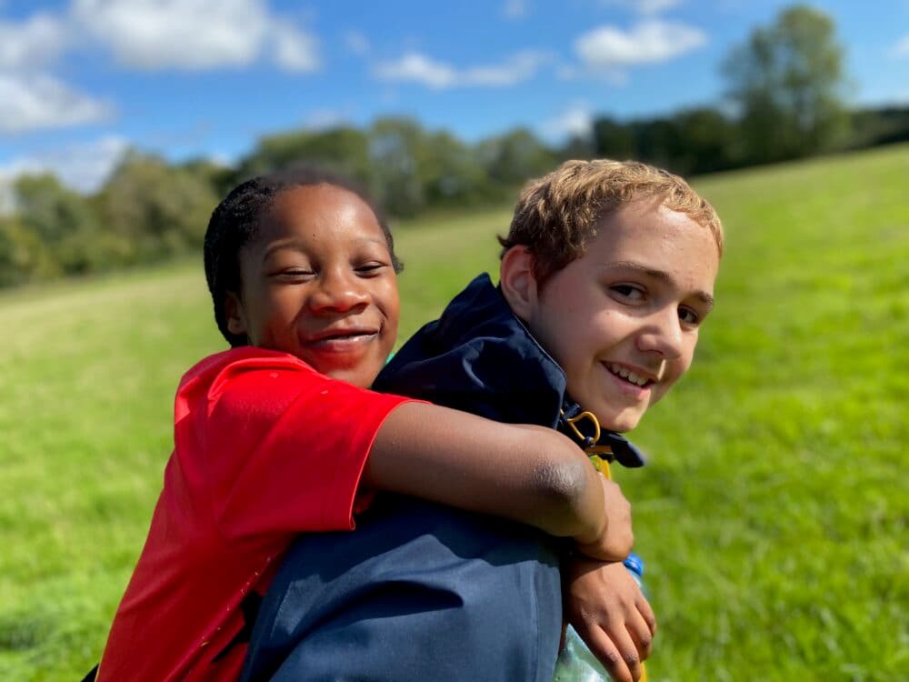 An older boy giving a piggy back to a younger girl during Walk the Test Way