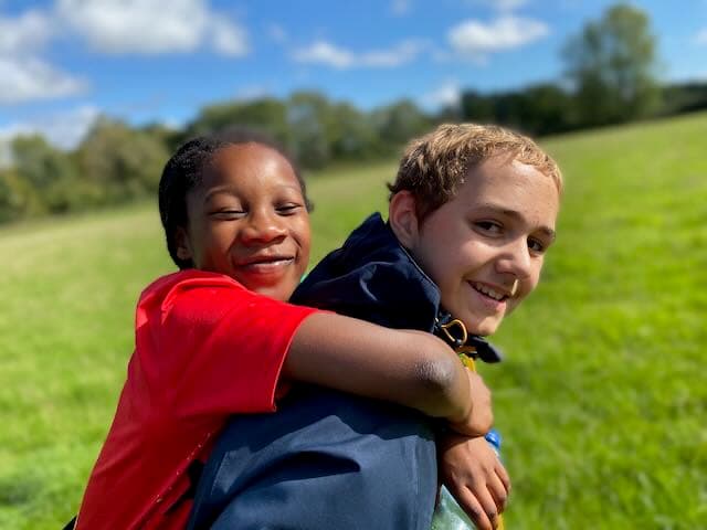 An older boy giving a piggy back to a younger girl during Walk the Test Way