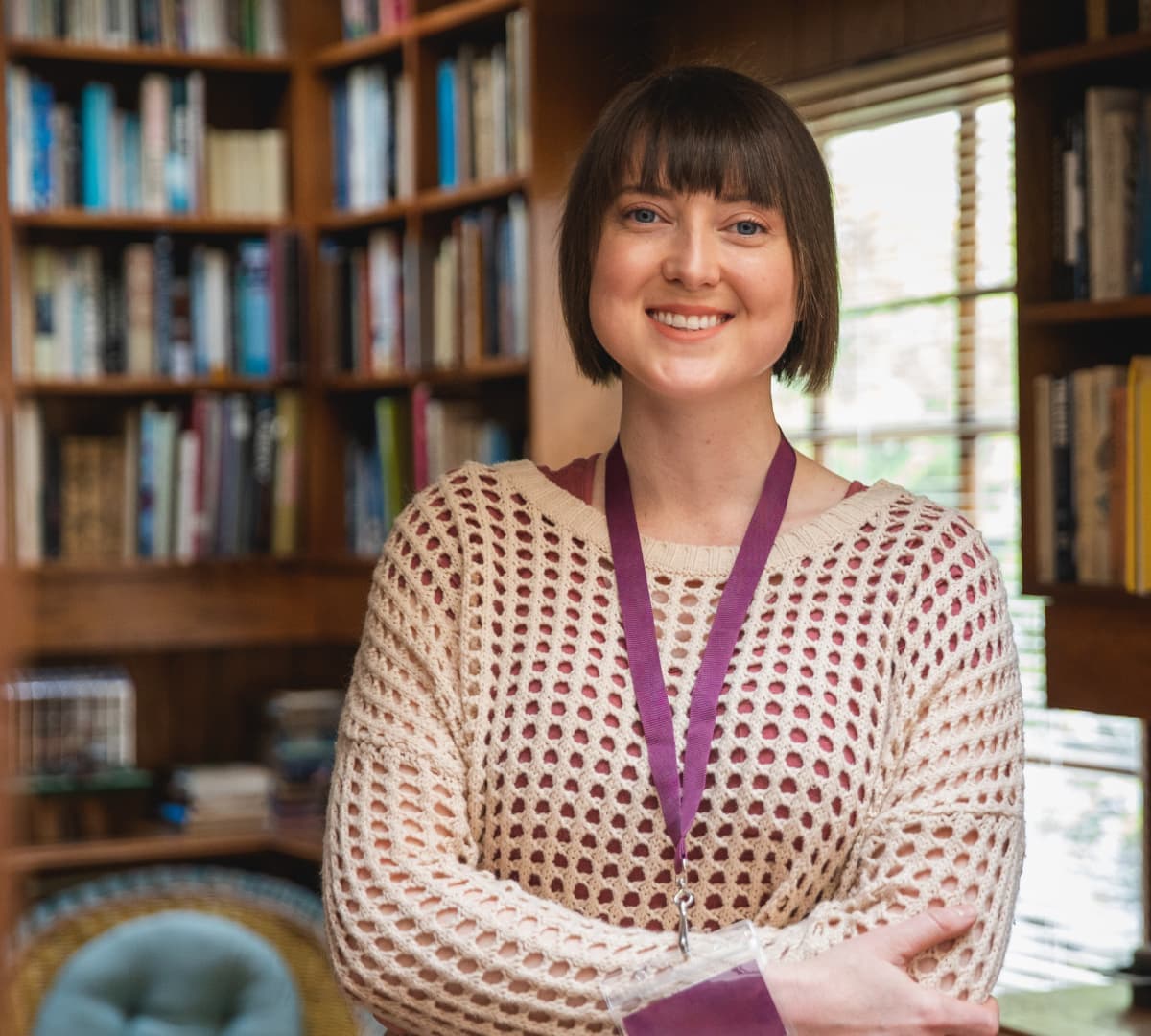 Carer with short hair happy and smiling while standing inside the house