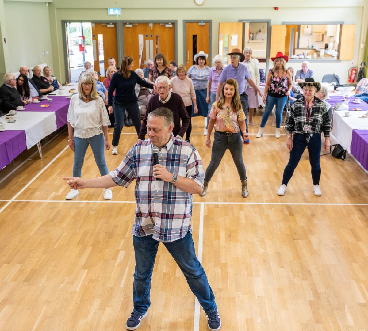 Many people inside a room dancing and having fun with their teacher teaching them how to dance