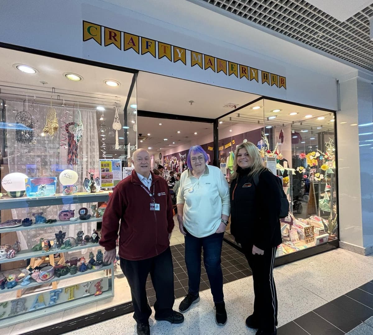 Three people smiling and standing in front of a craft store